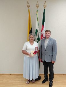 Direktorė su kunigu ir medaliu