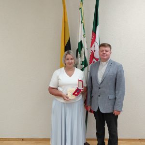 Direktorė su kunigu ir medaliu